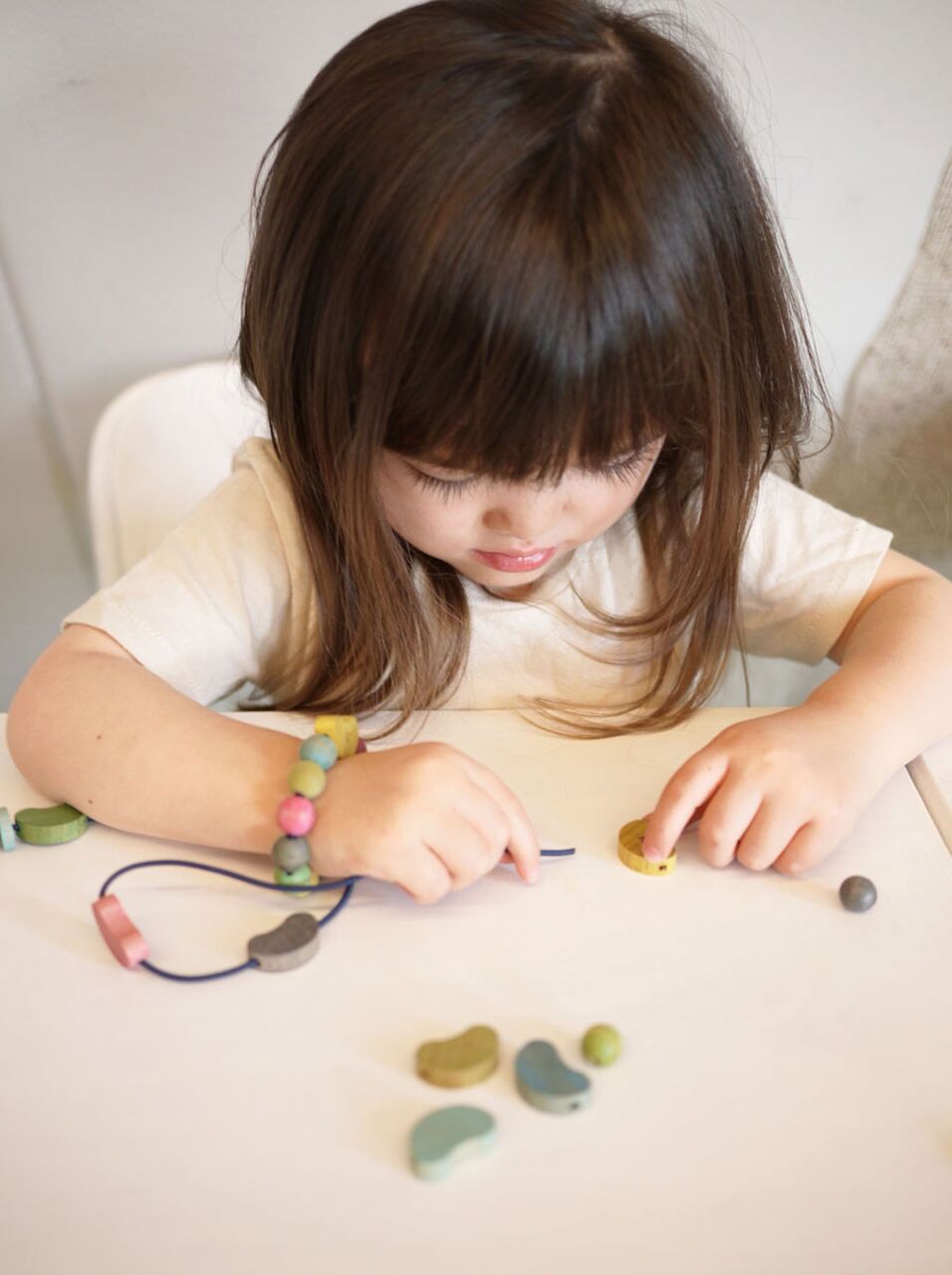 a little girl making a necklace